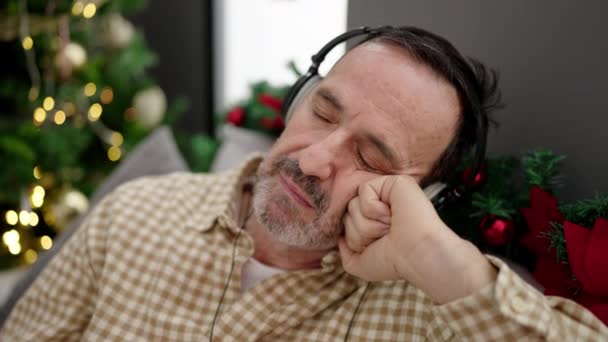 Muž Středního Věku Poslouchá Hudbu Spící Pohovce Vánočního Stromku Doma — Stock video