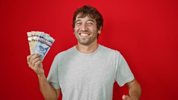 쾌활한 남자는 활기찬 빨간색 배경에 캐나다 지폐를 괜찮은 기호를 미소를 — 비디오