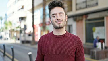 Sokakta kendinden emin gülümseyen İspanyol genç adam.