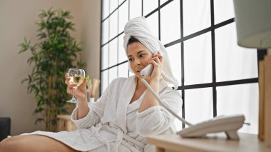 Bornoz giyen, şampanya içen, telefonda konuşan genç, güzel İspanyol kadın.