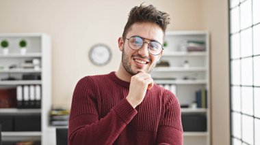 Genç İspanyol iş adamı ofiste kendinden emin gülümsüyor.