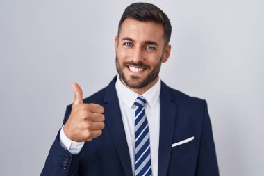 Yakışıklı İspanyol takım elbiseli ve kravatlı adam elinle mutlu bir jest yapıyor. Kameraya bakıp başarıyı gösteren ifade. 