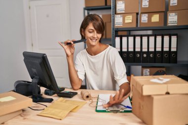 Young beautiful hispanic woman ecommerce business worker doing manicure at office