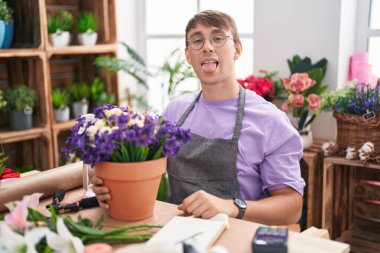 Beyaz, sarışın bir adam çiçekçide çalışıyor. Komik bir ifadeyle dilini dışarı çıkarıyor. duygu kavramı. 