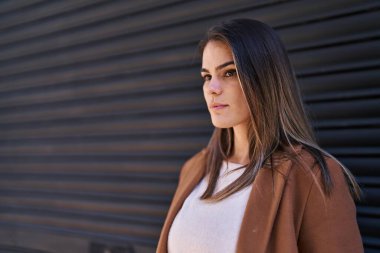 Genç, güzel İspanyol bir kadın, izole edilmiş Black Metal arka planında ciddi bir ifadeyle yan tarafa bakıyor.