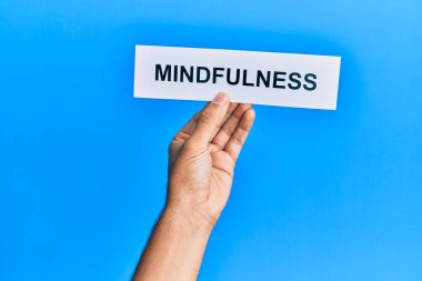 Hand of caucasian man holding paper with mindfulness word over isolated blue background
