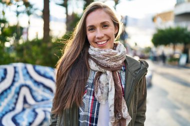 Parkta kendinden emin gülümseyen genç sarışın kadın.