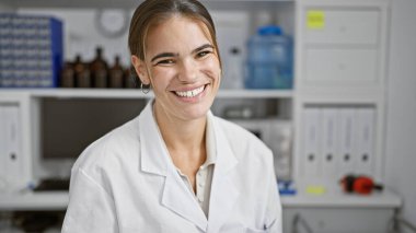 Laboratuvarda tıbbi araştırmalara gülümserken neşeli anların tadını çıkaran kendinden emin genç İspanyol bilim kadını mutluluğun ve bilimin güzel bir portresi.