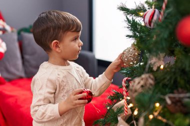 Evde Noel ağacı süsleyen sevimli İspanyol çocuk.