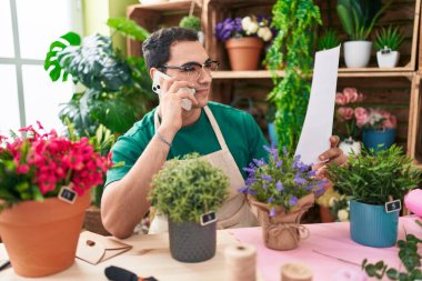 Çiçekçide akıllı telefondan konuşan İspanyol bir çiçekçi.
