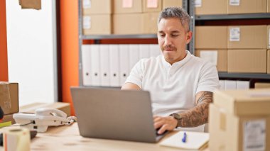 Ofiste dizüstü bilgisayar kullanan Latin asıllı genç bir iş adamı.