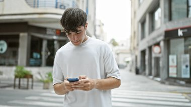 Havalı, genç İspanyol bir erkek ciddi görünüyor. Şehir merkezindeki bir sokakta akıllı telefonuyla mesajlaşırken konsantre oluyor.