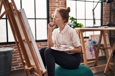 Resim stüdyosunda resim çizen genç sarışın kadın sanatçı.
