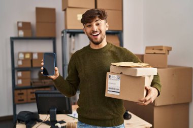 Sakallı bir Arap, elinde teslimat paketleriyle küçük bir şirkette çalışıyor. Gülmekten kırılıyor ve kahkahalarla gülüyor.. 