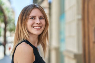 Sokakta kendine güvenen genç sarışın kadın gülümsüyor