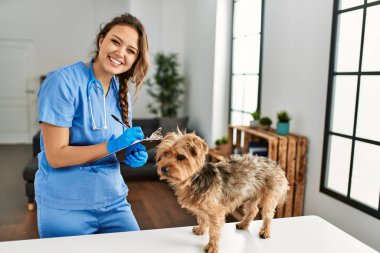 Genç ve güzel İspanyol kadın veteriner evde köpek yazma raporunu inceliyor.