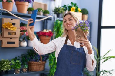 Young blonde woman florist make selfie by smartphone holding lavender plant at florist