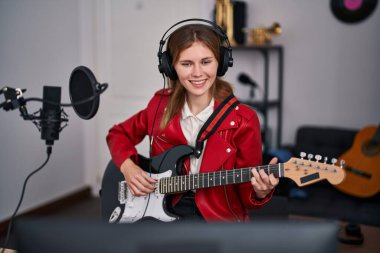 Genç sarışın müzisyen müzik stüdyosunda elektro gitar çalıyor.