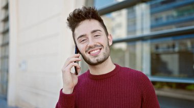 Genç İspanyol adam gülümsüyor. Kendine güveniyor. Sokakta akıllı telefondan konuşuyor.