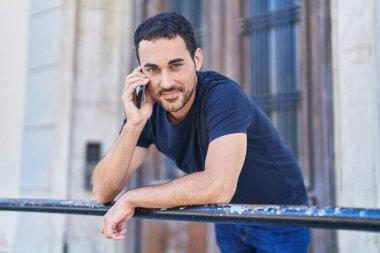 Genç İspanyol adam gülümsüyor. Kendine güveniyor. Sokakta akıllı telefondan konuşuyor.