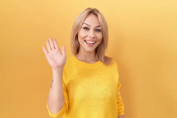 黄色いセーターを身に着けている若い白人女性は こんにちはハッピーで笑顔 フレンドリーな歓迎のジェスチャーを言います — ストック写真