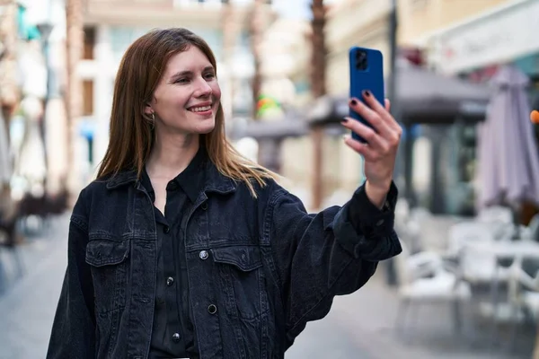 Young blonde woman smiling confident making selfie by the smartphone at street