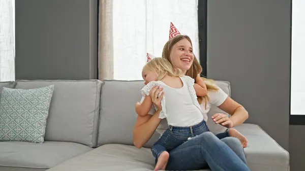 当他们舒舒服服地放松下来 坐在客厅沙发上欢快地笑着 一起在家里庆祝一个喜庆的生日的时候 他们的母亲和女儿紧紧地拥抱在一起 — 图库照片