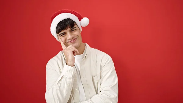 Молодой Латиноамериканец Уверенно Улыбающийся Рождественской Шляпе Изолированном Красном Фоне — стоковое фото