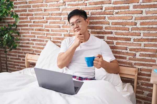 Ung Asiatisk Mand Drikker Kaffe Sidder Sengen Alvorligt Ansigt Tænker - Stock-foto