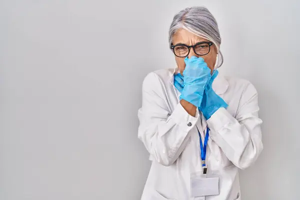 科学者服を着た灰色の髪を持つ中年の女性は 臭いと嫌な臭い 耐え難い臭いを嗅ぎ 鼻に指で息を止めています 悪い匂いがする — ストック写真