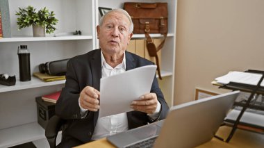 Ciddi, olgun, çalışkan, zarif, beyaz saçlı, tecrübeli bir iş adamı, ofiste ciddi bir şekilde konuşurken belgelere dalmış..