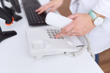 Eczanede bilgisayar kullanarak telefonu tutan güzel bir kadın eczacı.