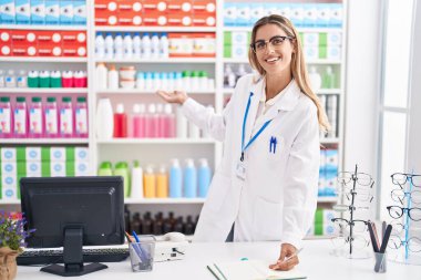 Young blonde woman pharmacist writing on document at pharmacy