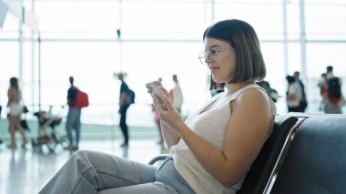 Havaalanında akıllı telefon kullanan genç ve güzel bir İspanyol kadın.