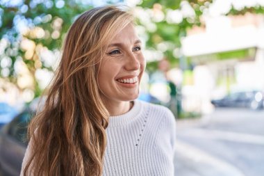 Young blonde woman smiling confident looking to the side at street