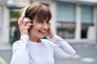 Sokakta müzik dinleyen orta yaşlı bir kadın.