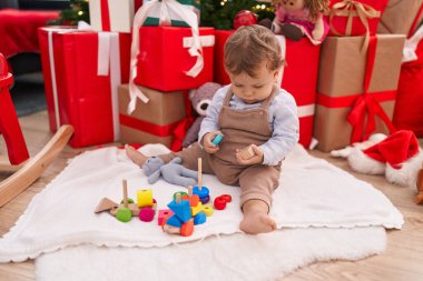 Sevimli sarışın çocuk evde Noel hediyeleriyle yerde oyuncaklarla oynuyor.