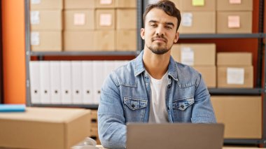 Ofiste dizüstü bilgisayar kullanan Latin asıllı genç bir iş adamı.