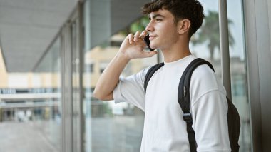 Sırt çantasıyla önemli bir telefon görüşmesi yapmak için akıllı telefonu kullanan sıradan bir İspanyol üniversite öğrencisi. Güneşli şehir kampüsünde durmuş, sohbete dalmış..