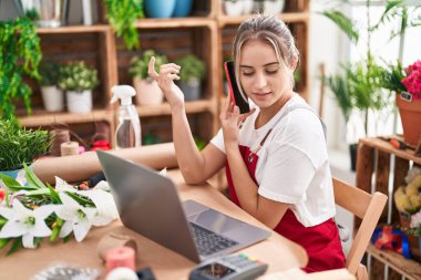 Çiçekçide bilgisayarla konuşan sarışın bir çiçekçi.