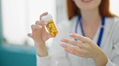 Genç kızıl saçlı kadın doktor klinikte reçete yazıyor.