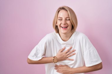 Pembe arka planda duran beyaz bir kadın var. Gülümsüyor ve kahkahalarla gülüyor.. 