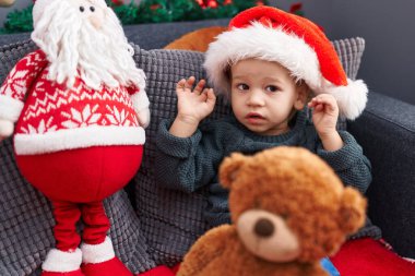 Sevimli sarışın bebek koltukta oturuyor. Evde Noel şapkası takıyor.