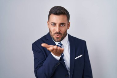Yakışıklı, takım elbiseli ve kravatlı bir adam kameraya bakıp havada el sallıyor ve çok seksi. aşk ifadesi. 