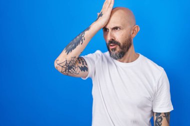 Mavi arka planda dikilen İspanyol dövmeli bir adam hata yaptığı için şaşırdı. Hatayı hatırla. Unuttum, kötü hafıza kavramı. 