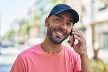 Genç kel adam gülümsüyor. Kendine güveni tam. Akıllı telefondan konuşuyor.