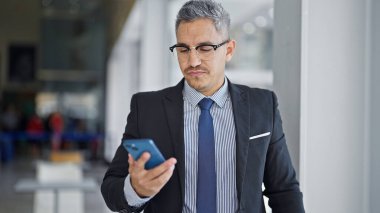 Young hispanic man business worker using smartphone at office