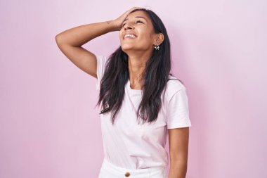 Pembe arka planda duran genç İspanyol kadın gülümsüyor. Kendine güvenen, el hareketleriyle saçlara dokunan, çekici ve modaya uygun poz veren. 