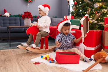 Geyiklerle oynayan sevimli çocuklar evde Noel hediyelerini açarken sallanıyorlar.