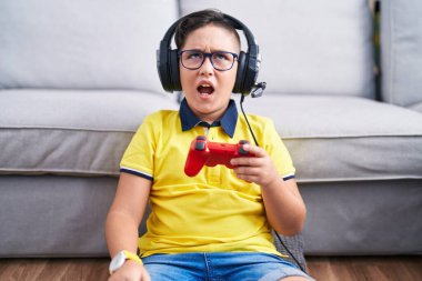 Kulaklık takıp bilgisayar oyunu oynayan genç İspanyol çocuk sinirli ve öfkeli çığlıklar atıyor, öfkeyle bağırıyor. öfke ve agresif konsept. 